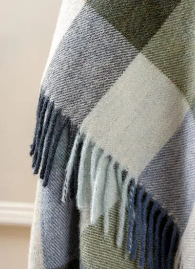 Close up of blue and green check lambswool throw draped across wooden chair